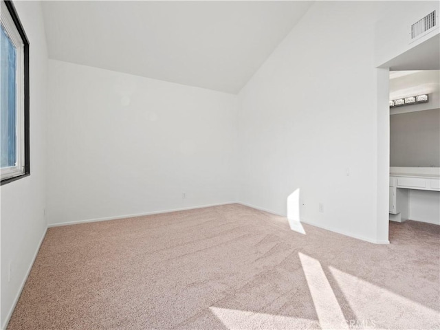 carpeted spare room with vaulted ceiling