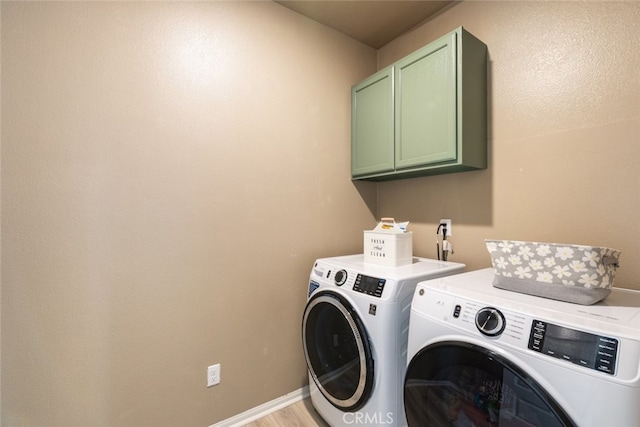 washroom featuring cabinets, light hardwood / wood-style floors, and washing machine and dryer