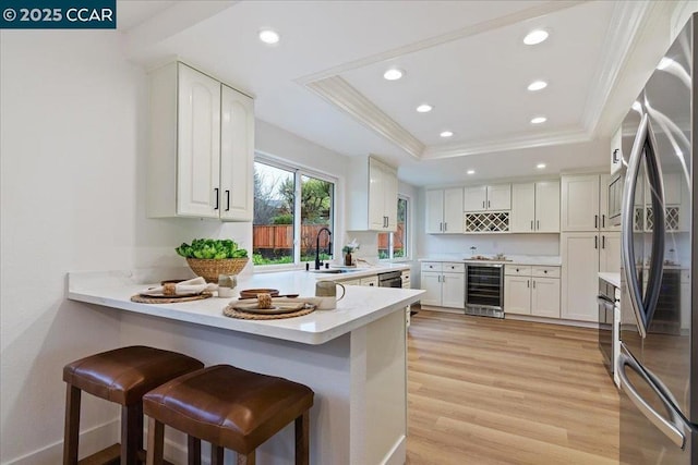 kitchen featuring a raised ceiling, stainless steel fridge, beverage cooler, and kitchen peninsula