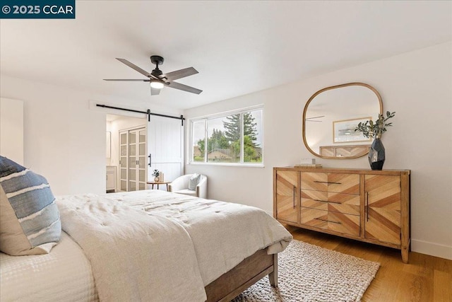 bedroom featuring hardwood / wood-style flooring, a barn door, and ceiling fan