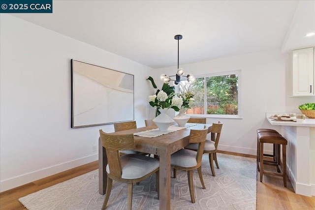 dining space with an inviting chandelier and light hardwood / wood-style flooring