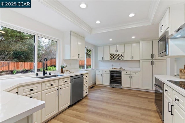 kitchen featuring sink, stainless steel appliances, a tray ceiling, white cabinets, and beverage cooler