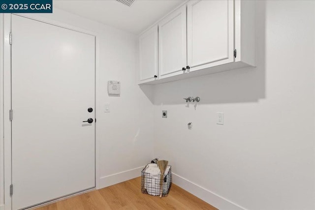 clothes washing area featuring electric dryer hookup, hookup for a washing machine, light hardwood / wood-style flooring, and cabinets