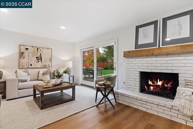 living room with a brick fireplace and wood-type flooring