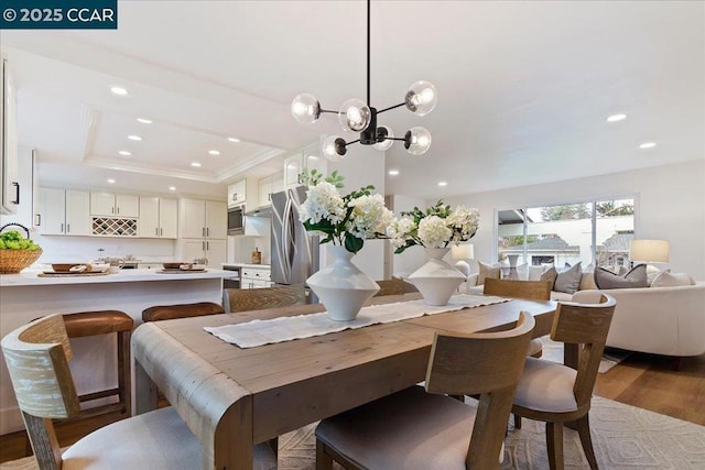 dining area with a raised ceiling, dark wood-type flooring, and an inviting chandelier