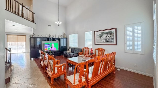 living room featuring a notable chandelier, a towering ceiling, tile patterned flooring, and a wealth of natural light