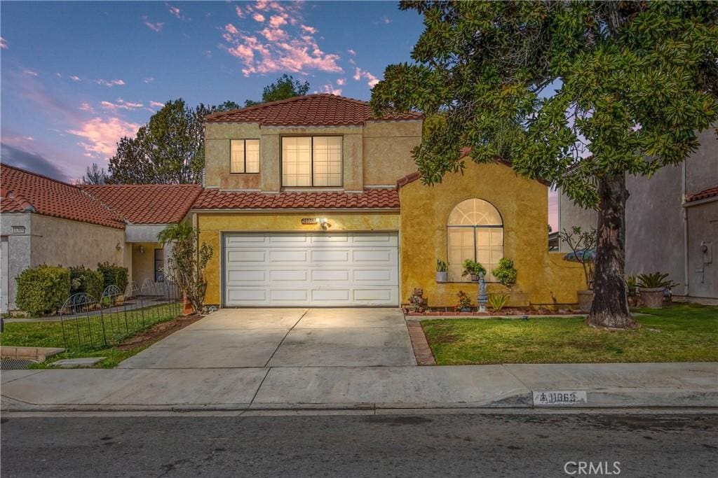 mediterranean / spanish-style home featuring a garage and a yard