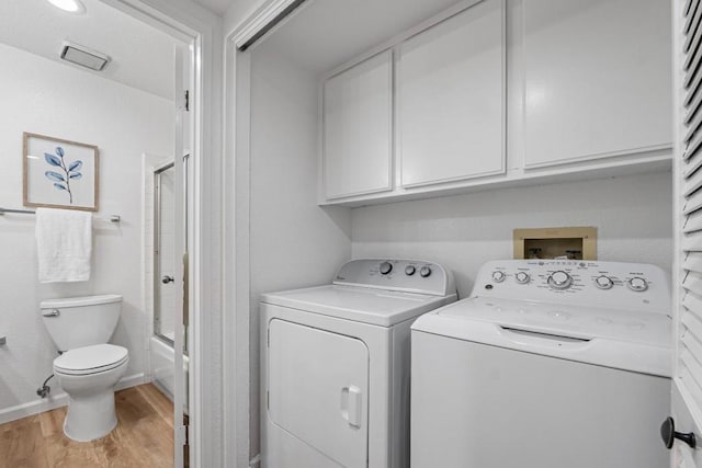 laundry room featuring cabinets, independent washer and dryer, and light wood-type flooring