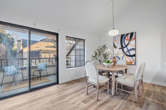 dining space featuring a healthy amount of sunlight, high vaulted ceiling, and wood-type flooring