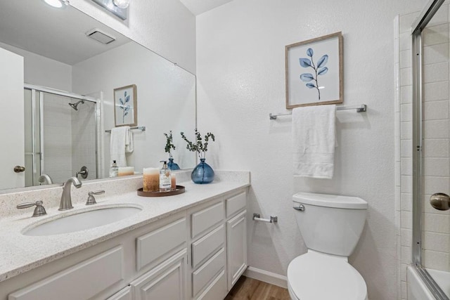 full bathroom featuring hardwood / wood-style flooring, vanity, toilet, and combined bath / shower with glass door