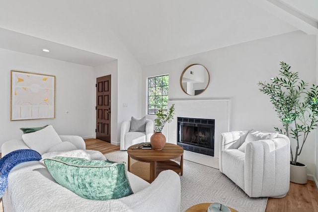 living room featuring a tile fireplace, vaulted ceiling, and light hardwood / wood-style flooring