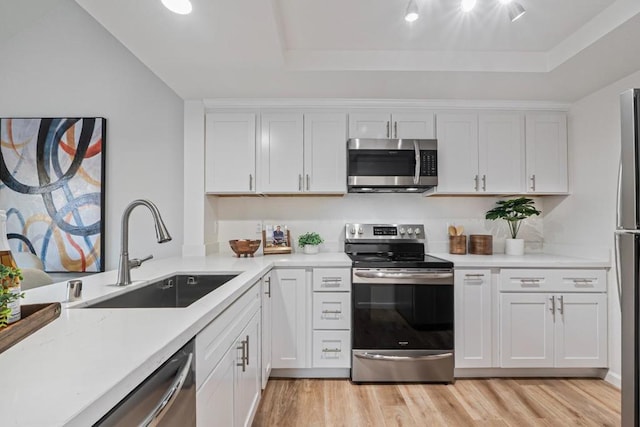 kitchen featuring light wood-type flooring, stainless steel appliances, sink, and white cabinets