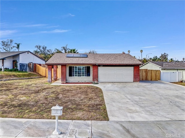 ranch-style house featuring a garage and solar panels