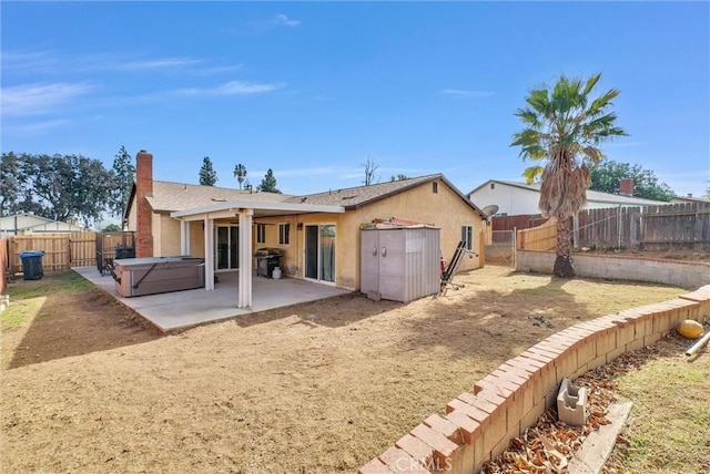 rear view of house with a hot tub and a patio area