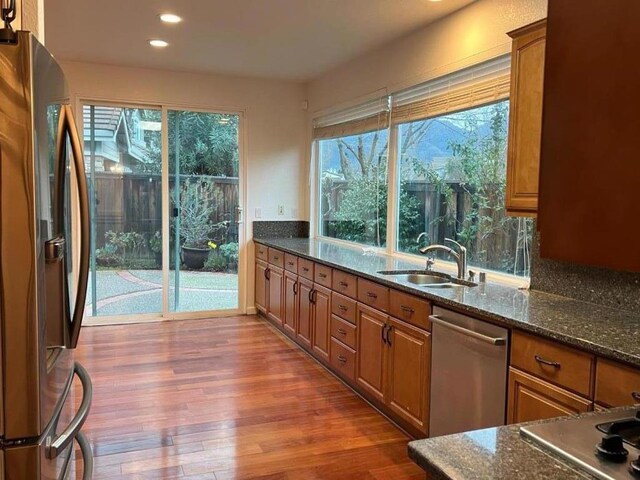 kitchen featuring appliances with stainless steel finishes, sink, and dark stone counters