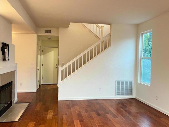 unfurnished living room featuring dark wood-type flooring and a fireplace