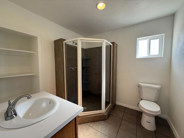 bathroom featuring tile patterned flooring, vanity, toilet, and walk in shower