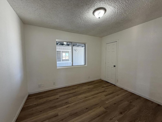 empty room featuring dark wood-type flooring and a textured ceiling