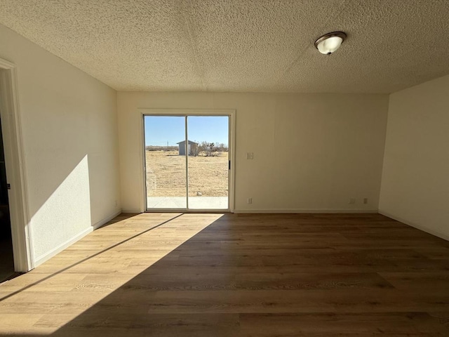 empty room featuring wood-type flooring and a textured ceiling