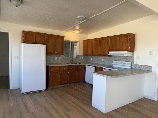 kitchen with tasteful backsplash, wood-type flooring, sink, kitchen peninsula, and white appliances