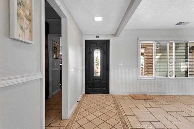 entryway featuring light tile patterned floors, plenty of natural light, and a textured ceiling