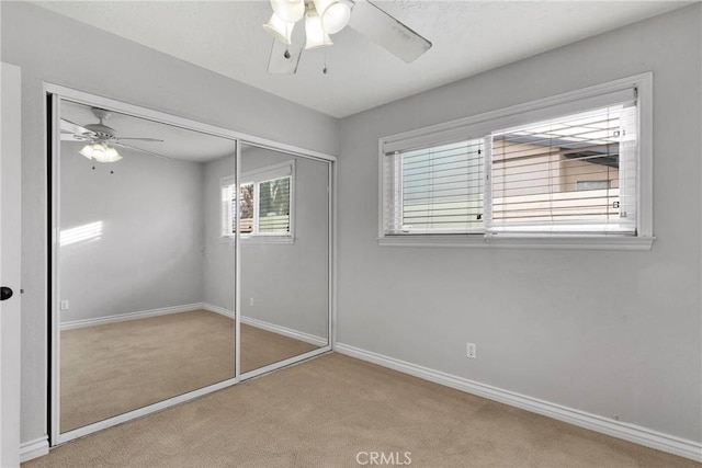 unfurnished bedroom with light carpet, ceiling fan, and a closet