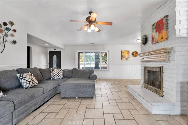 living room featuring a large fireplace and ceiling fan