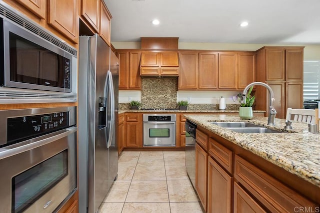 kitchen with sink, light stone counters, light tile patterned floors, appliances with stainless steel finishes, and decorative backsplash