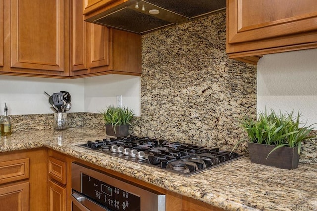 kitchen with light stone countertops, exhaust hood, and appliances with stainless steel finishes