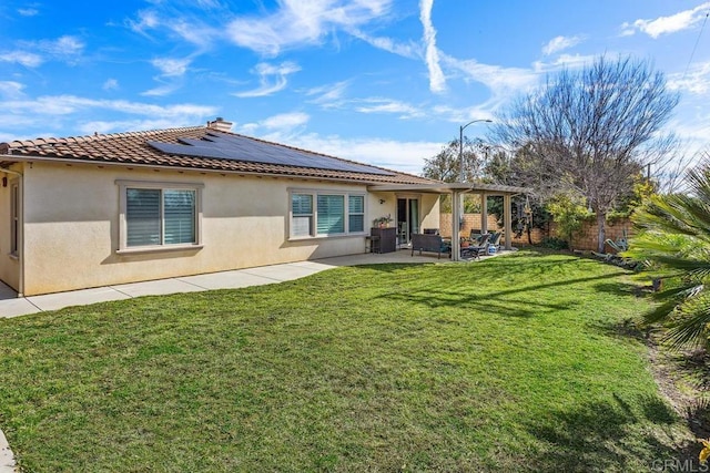 rear view of property featuring a yard, a patio, and solar panels