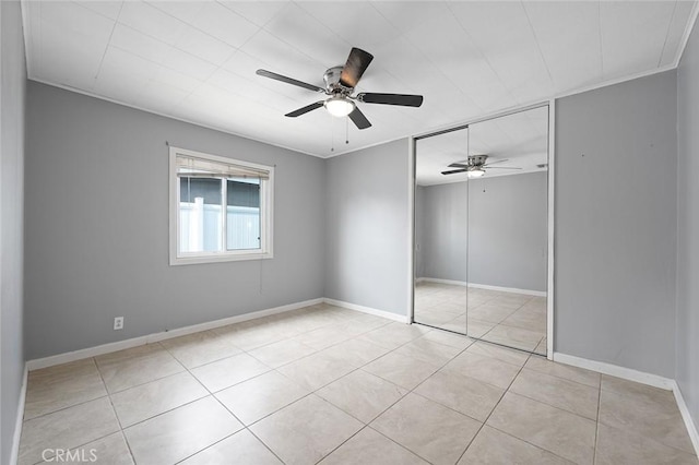 unfurnished bedroom with light tile patterned floors, ceiling fan, and a closet