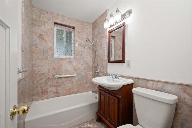 full bathroom with vanity, tiled shower / bath combo, tile walls, and toilet