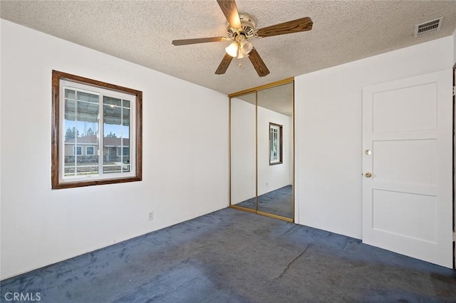 carpeted spare room featuring ceiling fan and a textured ceiling