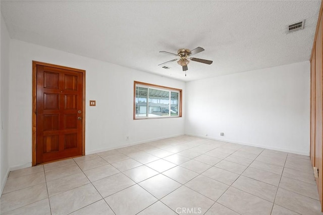 tiled spare room with a textured ceiling and ceiling fan