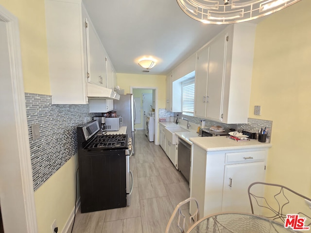 kitchen with sink, white cabinetry, tasteful backsplash, washer and dryer, and appliances with stainless steel finishes