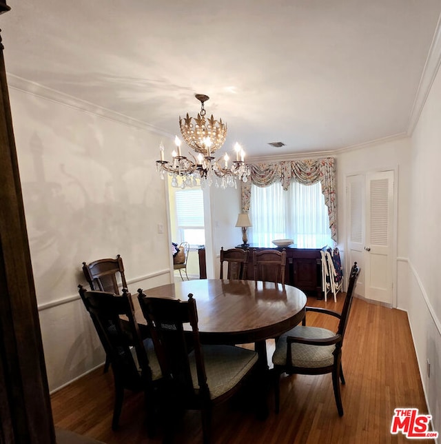 dining space featuring an inviting chandelier, hardwood / wood-style flooring, and ornamental molding