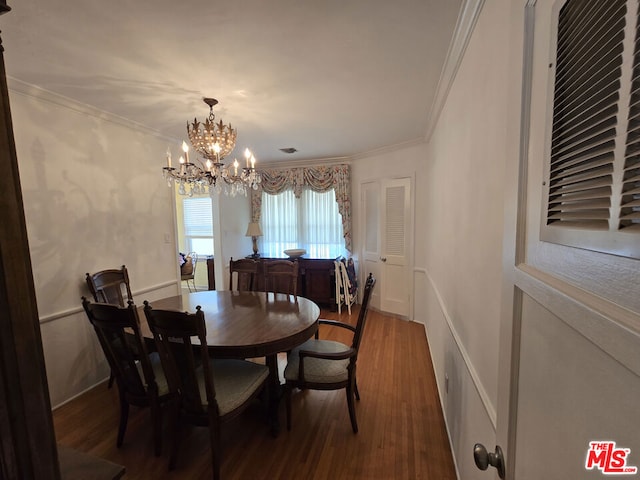 dining room featuring ornamental molding, wood-type flooring, and a notable chandelier