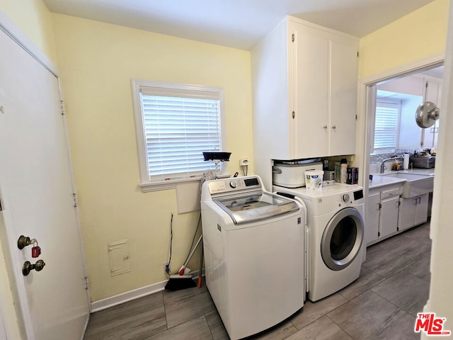 clothes washing area featuring independent washer and dryer, cabinets, and sink