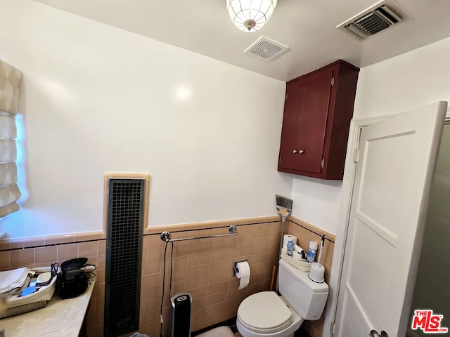 bathroom featuring heating unit, tile walls, and toilet