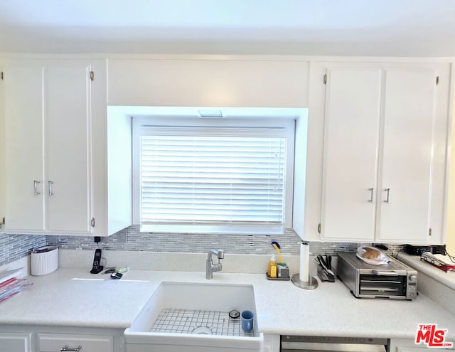 kitchen with white cabinetry, dishwasher, sink, and decorative backsplash