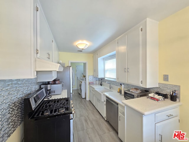 kitchen featuring stainless steel appliances, separate washer and dryer, decorative backsplash, and white cabinets