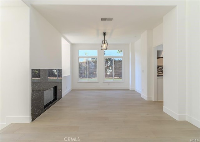 unfurnished living room featuring a fireplace and light hardwood / wood-style floors