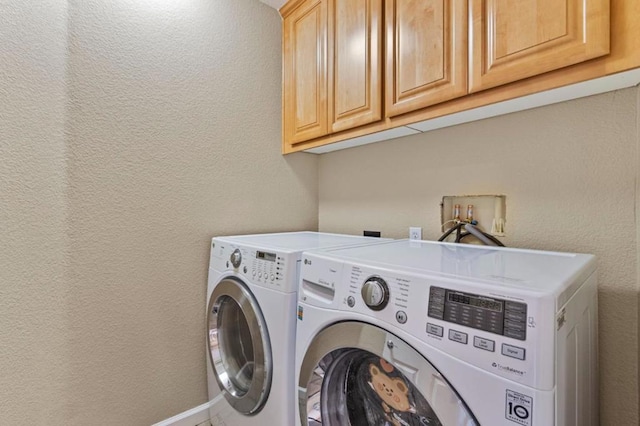 clothes washing area with cabinets and washing machine and dryer