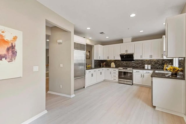 kitchen featuring white cabinetry, stainless steel appliances, light wood-type flooring, and backsplash