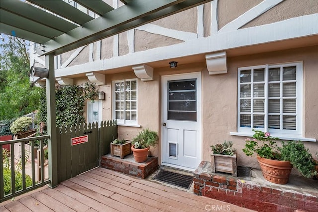 entrance to property featuring a pergola and stucco siding