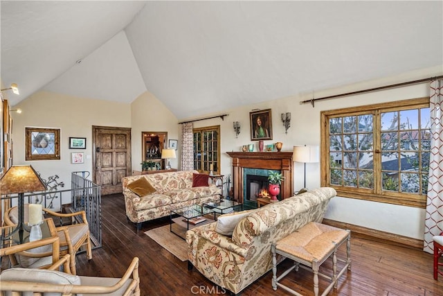 living area with lofted ceiling, a fireplace, baseboards, and wood finished floors