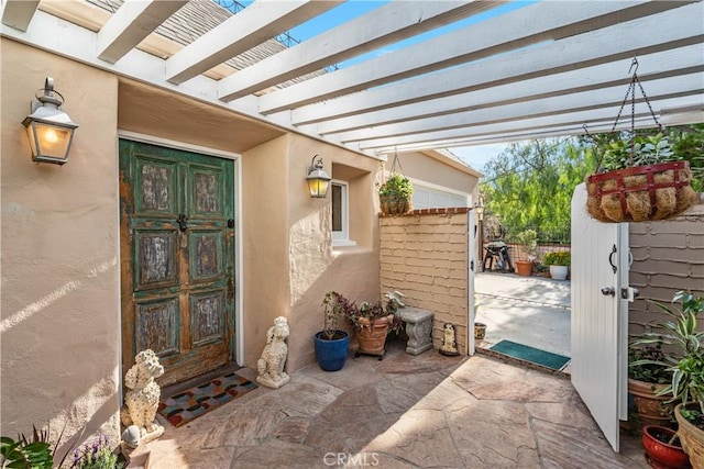 doorway to property featuring a patio, a pergola, and stucco siding