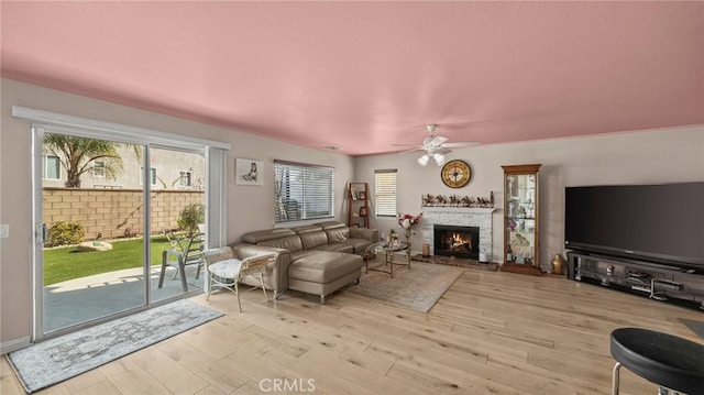 living room featuring a brick fireplace, light hardwood / wood-style flooring, and ceiling fan