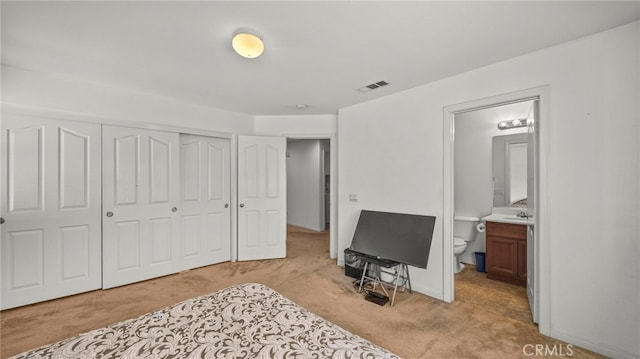 carpeted bedroom featuring sink, ensuite bath, and a closet