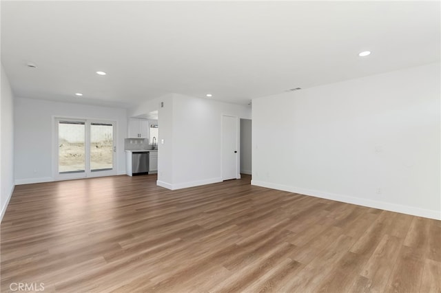 unfurnished living room with sink and light hardwood / wood-style floors